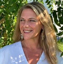 Eileen Day McKusick Smiling In front of A Tee Biofield Tuning Practitioner Healer