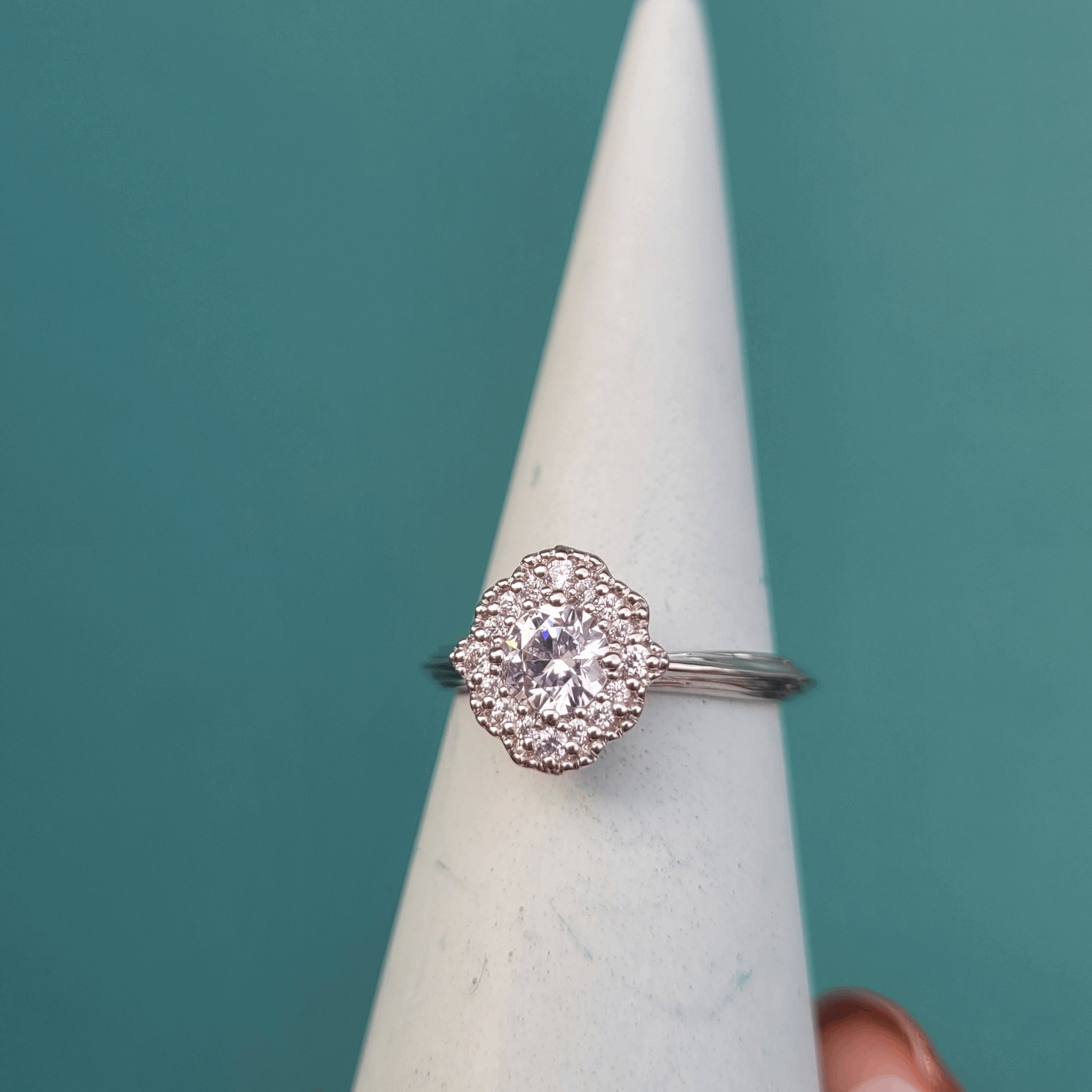 Vintage Inspired Enchanted Rose mandala shaped halo engagement ring available in natural or lab grown diamonds with an organic detail band and milgrain detail edge by Emma Hedley Custom Jeweller  blue background based in Newcastle Upon Tyne with a raised setting to fit next to a wedding ring