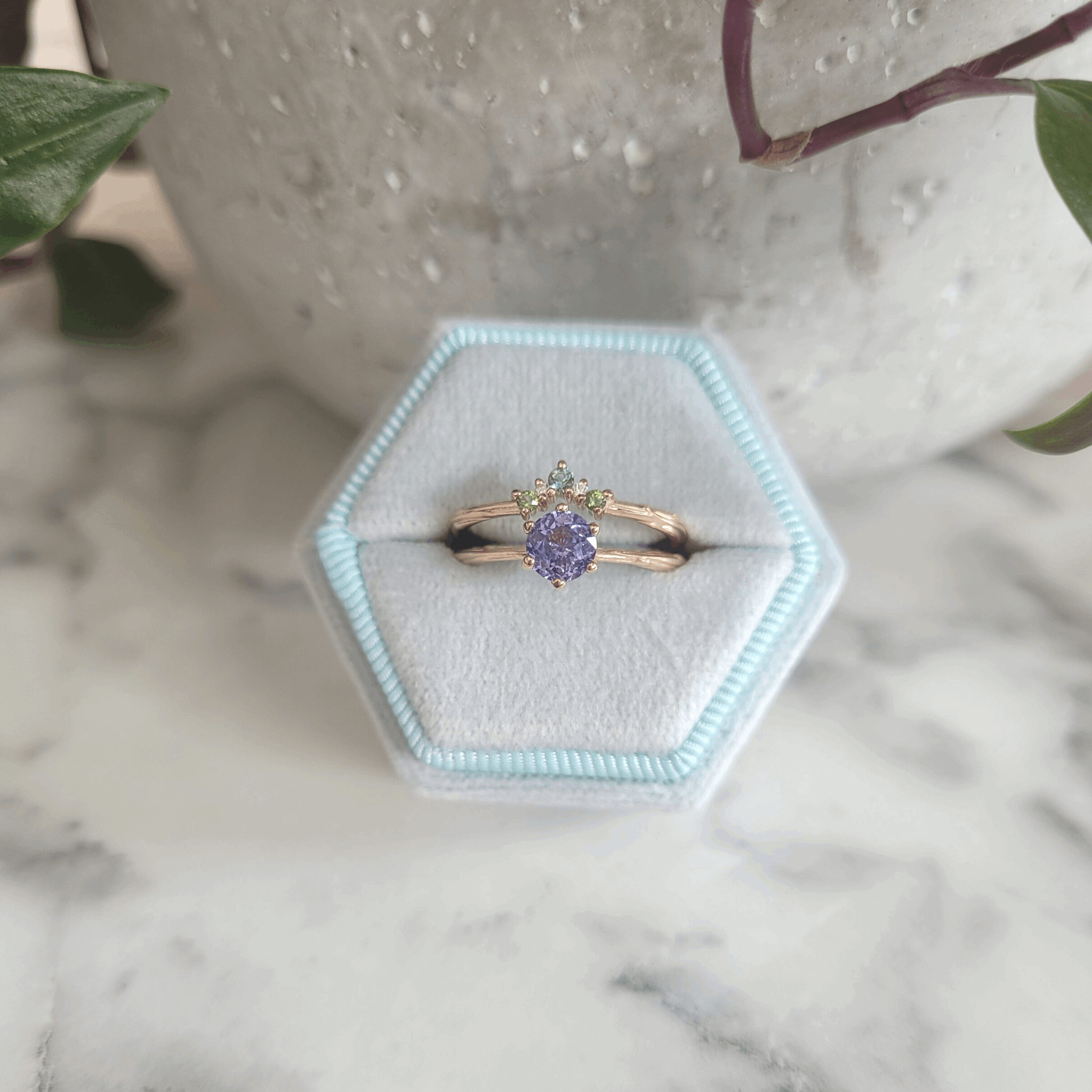 Organic Caress wedding eternity shaped 5 stone Ring recycled 9ct rose gold set with green and blue tourmaline ethically sourced gemstones next to a lilac purple sapphire engagement ring natural diamonds by Emma Hedley colourful unique alternative wedding and engagement rings custom made to order