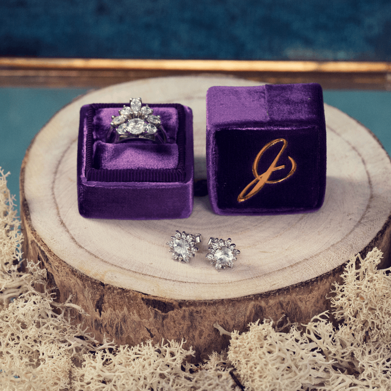 18ct Fairtrade white gold diamond and sapphire halo stud cluster earrings- by British fine jewellery designer Emma Hedlley next to a luxurious vintage style purple velvet ring box with custom diamond wedding and engagement rings