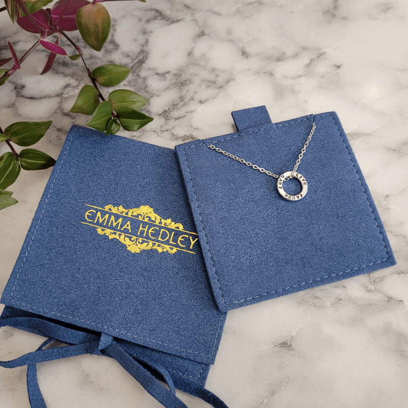 Dainty Hoop Personalised Hand Stamped necklace displayed on recycled ocean plastic suede like pouch in blue. Handmade by Emma Hedley Jewellery Designer
