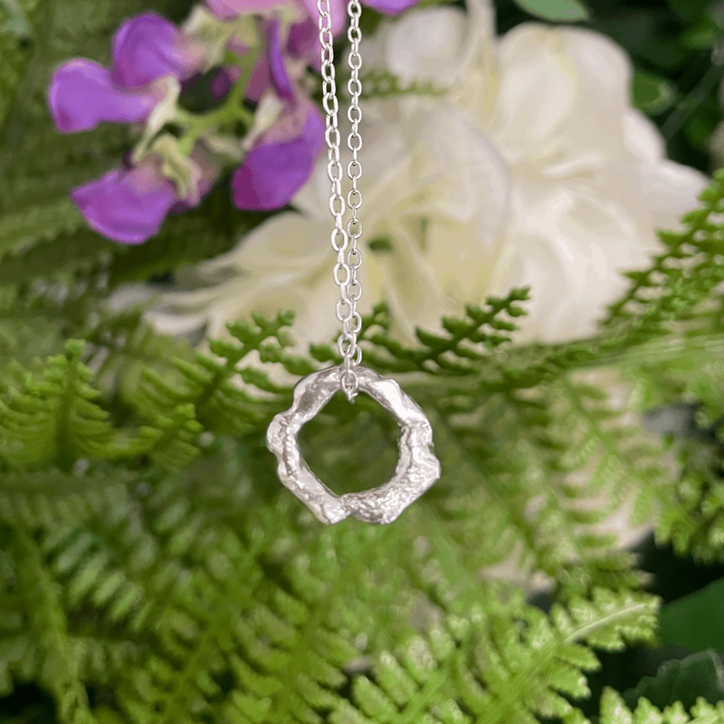 Melted Hoop Pendant using recycled sterling silver hanging on a silver trace chain in front of foliage. Handmade by Emma Hedley Jewellery Designer