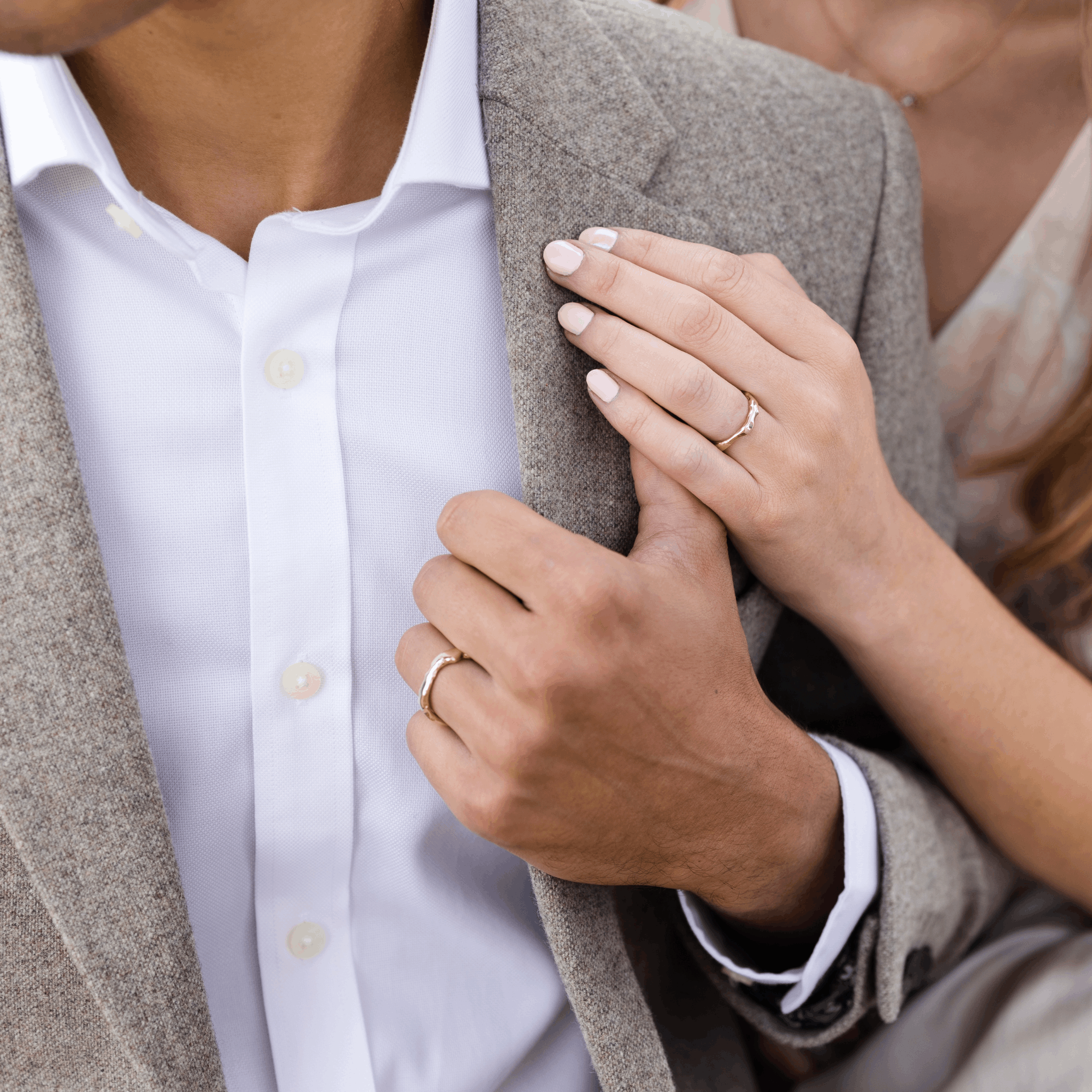 Man and woman's hands wearing the Melted textured wedding rings by Fine jewellery Designer Emma Hedley