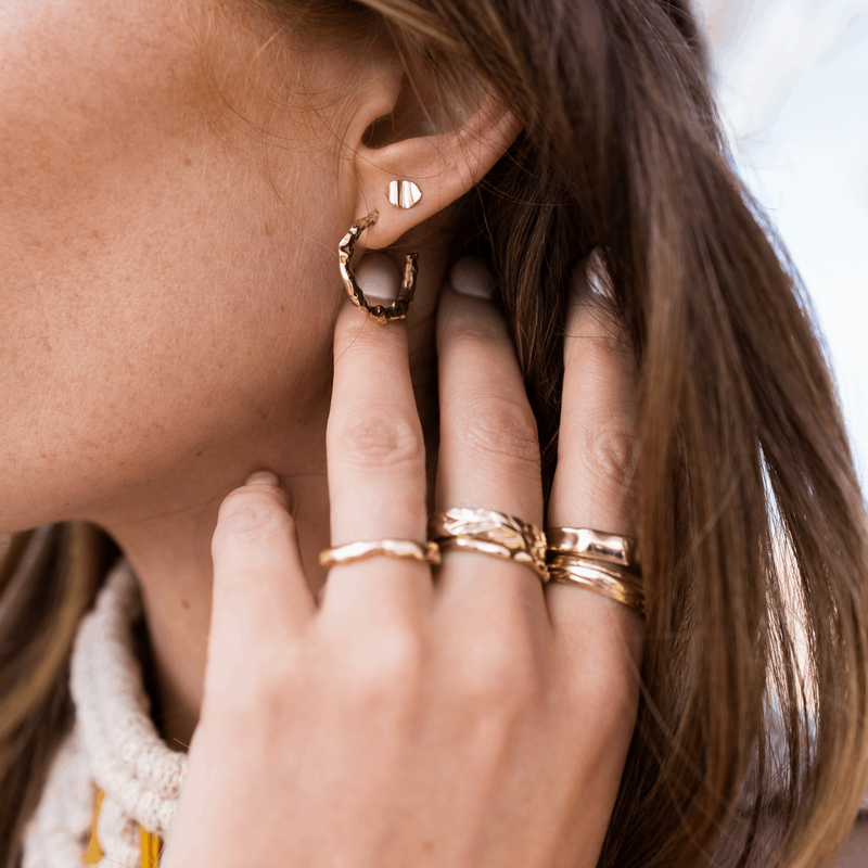 Melted yellow gold recycled hoop earrings with ripple stud earrings and stack of textured stacking rings by fine jewellery designer Emma Hedley Photography by Claire Collinson
