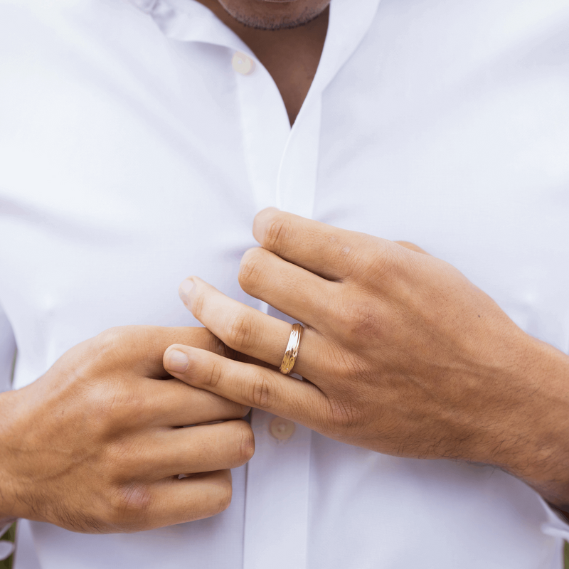 Gent's hands wearing an Organic textured 5mm recycled yellow gold wedding ring whilst buttoning a white shirt 