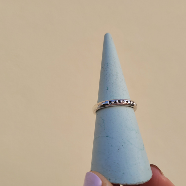 Personalised Sterling Silver Lyric Ring hand stamped with a custom message on a blue ring cone. Handmade by Emma Hedley Artisan Jeweller