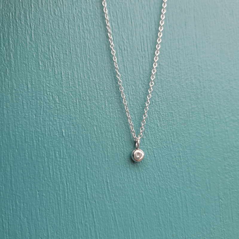 small sterling silver letter R initial pendant on a trace chain by Jewellery Designer Emma Hedley on a teal background