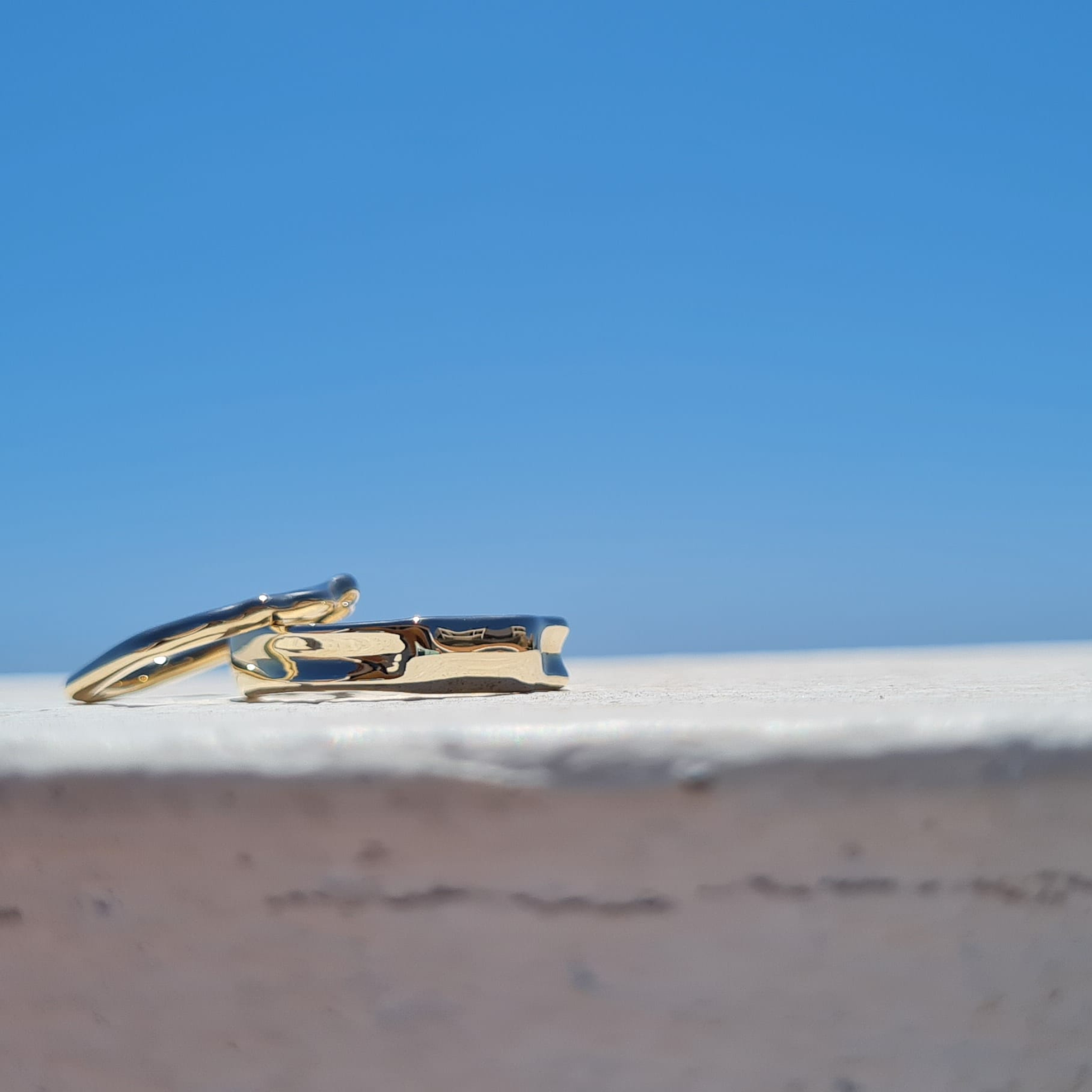 unique wedding rings against a blue sky water inspired Ripple textured rings 2mm and 5mm wide unisex his and hers rings designed by Jeweller Emma Hedley
